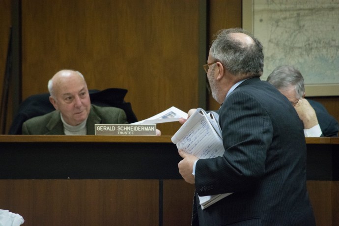 A representative hands out photos of the proposed Maple Drive development. (Photo by Janelle Clausen)