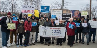 Residents briefly held up signs protesting Trump administration policies on Martin Luther King's birthday, saying things like "We are all immigrants" and "The opposite of love is not hate... It's indifference." (Photo by Janelle Clausen)