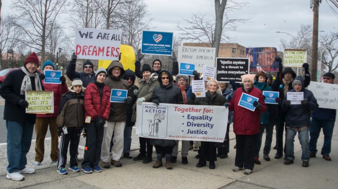 Residents briefly held up signs protesting Trump administration policies on Martin Luther King's birthday, saying things like "We are all immigrants" and "The opposite of love is not hate... It's indifference." (Photo by Janelle Clausen)