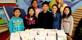 Third graders from Ms. Victoria Weiss’s class are photographed with cards created by Lakeville students. (Photo courtesy of the Great Neck Public Schools)