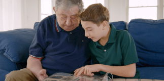 Elliot and Jack, a Holocaust survivor, sit together on the couch while going through an old photo album in "The Number on Great-Grandpa's Arm." The film will be shown on April 22. (Photo courtesy of HBO documentary films)