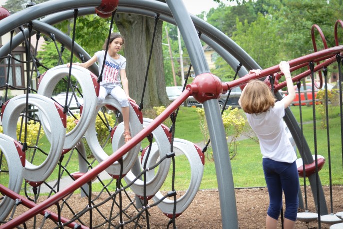 Two friends climb onto a fixture at the park at Village Green. (Photo by Janelle Clausen)