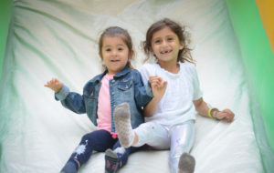 Two girls hold hands as they go down a giant inflatable slide together. (Photo by Janelle Clausen)