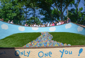 School staff, administrators and friends of the Portnoy family line up for a photo atop a new wall mural and stream of pavers. (Photo by Janelle Clausen)