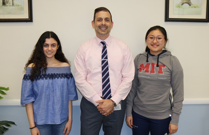 North High Principal Daniel Holtzman congratulates Courtney Hakimian and Megan Xu on being National Merit Scholars. (Photo courtesy of the Great Neck Public Schools)