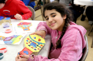 Fifth graders, including this girl in pink, painted colorful designs on paving stones for the new mindfulness area at Saddle Rock School. (Photo courtesy of the Great Neck Public Schools)