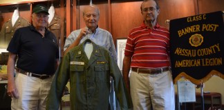 Anthony W. Buzzitta, flanked by two fellow veterans, holds up his old U.S. Army jacket. (Photo by Janelle Clausen)