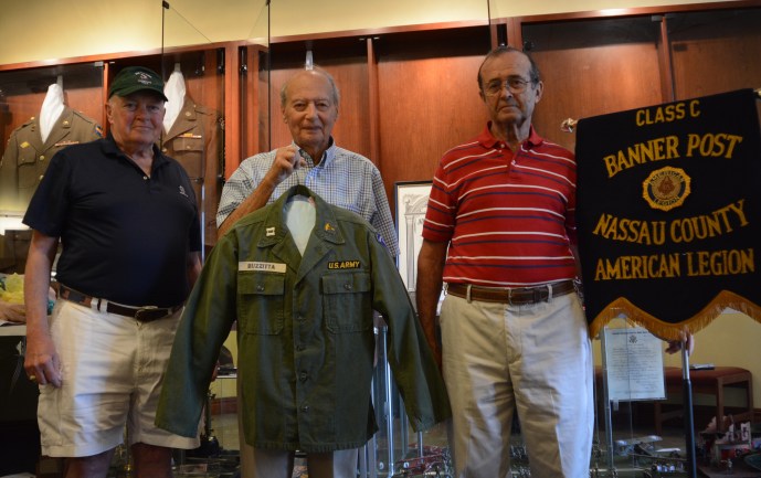 Anthony W. Buzzitta, flanked by two fellow veterans, holds up his old U.S. Army jacket. (Photo by Janelle Clausen)
