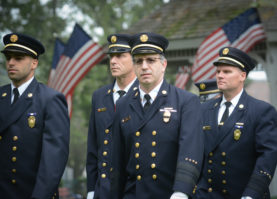 Vigilant Fire Chief Joshua Charry and other uniformed firefighters make their way into Firefighters Memorial Park. (Photo by Janelle Clausen)