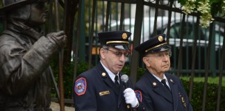 A statue of Jonathan L. Ielpi, a New York City firefighter from Great Neck, looms over Vigilant Fire Chief Joshua Charry as he addresses attendees, with his father Rabbi Marim Charry by his side. (Photo by Janelle Clausen)