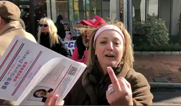 Mersedeh Rofeim holds campaign literature in one hand and raises a middle finger with the other toward Mimi Hu, who is recording the incident.