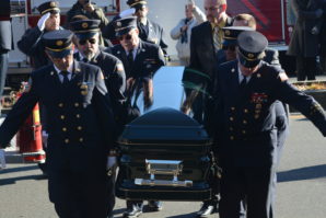 Tyler and Ryan Plakstis, Thomas McDonough Jr., and fire department officials carry Ray Plakstis up the steps of St. Aloysius Catholic Church. (Photo by Janelle Clausen)