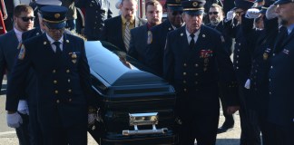 Tyler and Ryan Plakstis, Thomas McDonough Jr., and fire department officials carry Ray Plakstis up the steps of St. Aloysius Catholic Church. (Photo by Janelle Clausen)