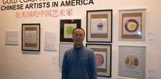 Shi Xiangdong standing in front of the his paintings stands in front of his work in the Gold Coast Art Center's new exhibit. (Photo by Demi Guo)