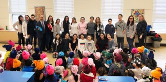 Eighth-graders from the North Middle School FACS program visited the John F. Kennedy School to deliver fleece hats and share a story with kindergarten students. Lauren Neckin, department chair for FACS, and her North Middle students are photographed with Kennedy School faculty Alyssa Gies, special education teacher; Christina Russo, kindergarten teaching assistant; Judy Friedman, kindergarten teacher; Ron Gimondo, principal; Michelle Reiter, kindergarten teacher; Gabby Kishinevsky, kindergarten teacher; and Michelle Bell, assistant principal. (Photo courtesy of the Great Neck Public Schools)