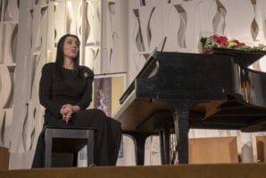 Tania Eshaghoff Friedberg, a SHAI board member, performer and event organizer, breaks away from the piano to address the crowd. (Photo by Laurence Hahn of HR Media Group)