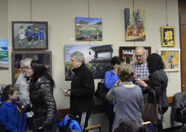 Artists, family and friends examine the work on display in Great Neck Plaza Village Hall. (Photo by Janelle Clausen)