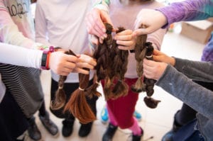 Donors hold samples of hair that will go toward creating wigs for children with cancer in Israel. (Photo by Eli Schilowitz)