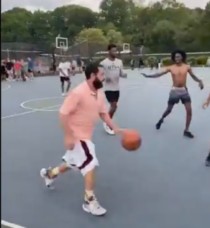 Comedian Adam Sandler, in orange, dribbles during a pickup basketball game with locals at Christopher Morley Park in Roslyn. (Screencap via Instagram, @RoboBball3)